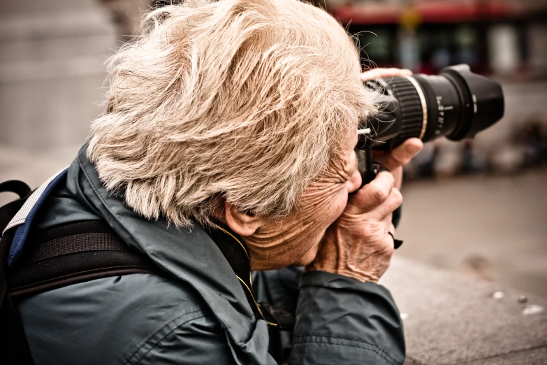 an old woman with white hair taking pictures with a camera