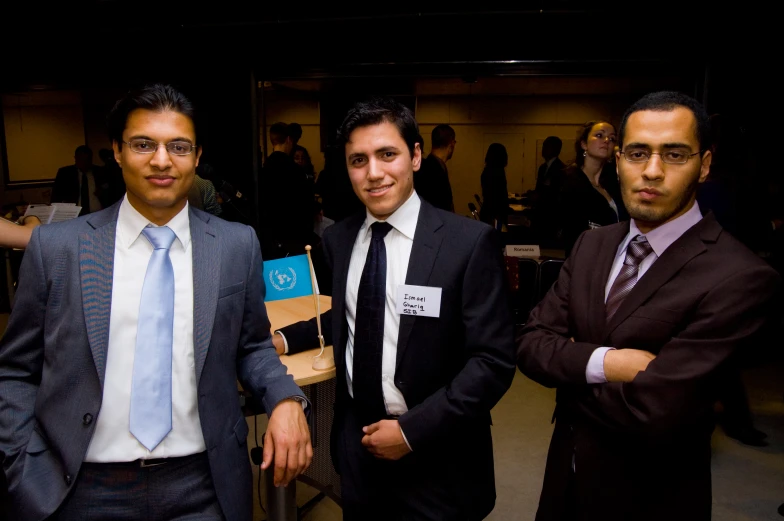 three men in suits and ties stand together with one holding up the other