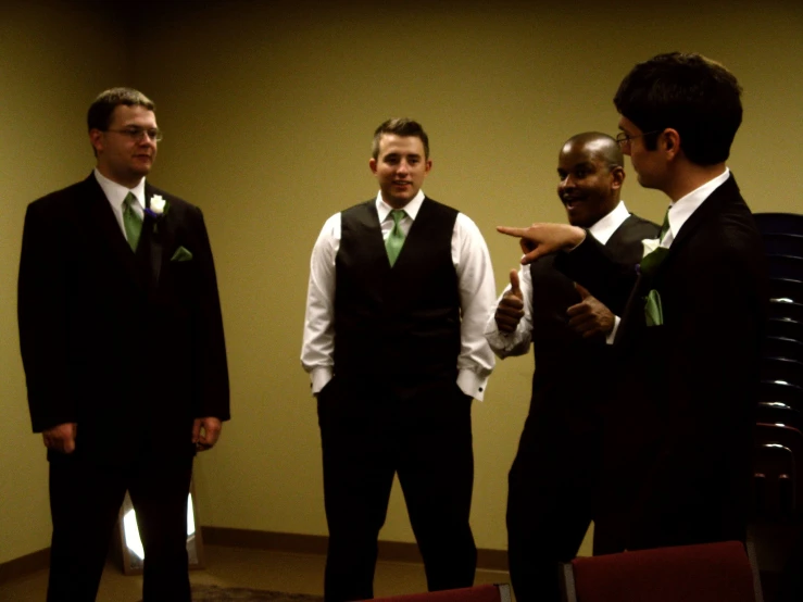 three men in suits standing with one pointing to another