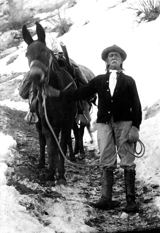 black and white po of boy standing near horses