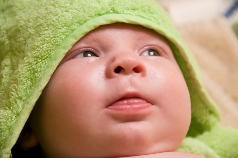 a baby wearing a towel looks upward