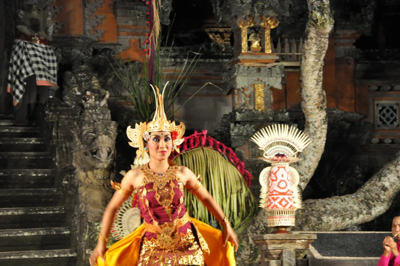 a woman with elaborate headdress performing a cultural act