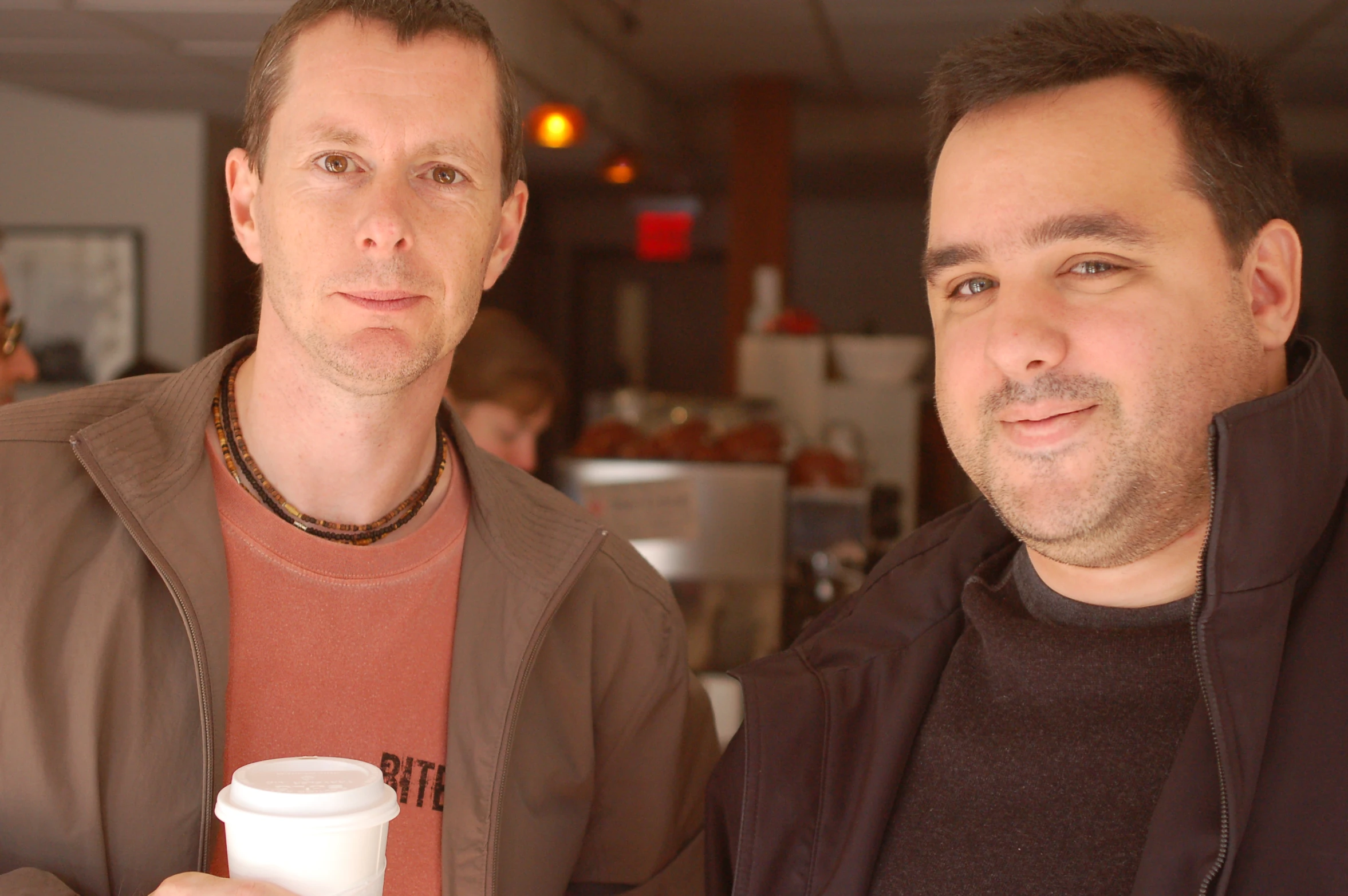 a couple of men standing in a restaurant holding glasses of drink