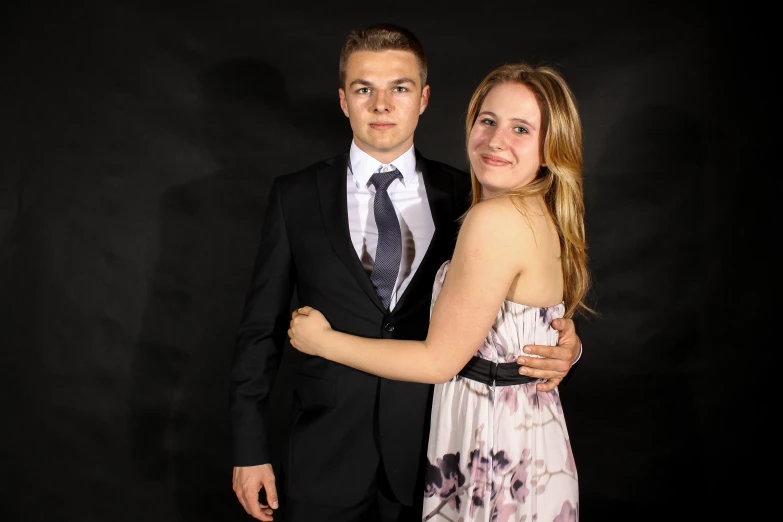 a woman in a pink dress and a man in a black suit posing for a po