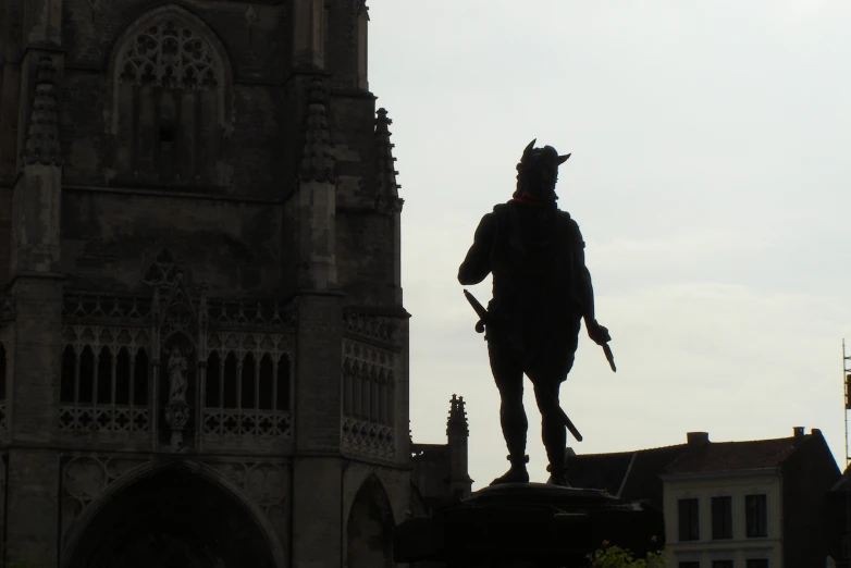 silhouette of a statue near a large castle like structure