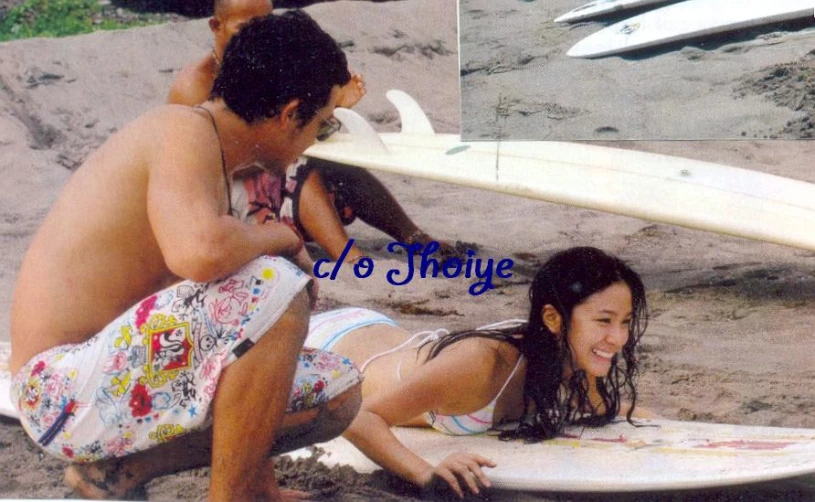 two people on a beach next to a surfboard