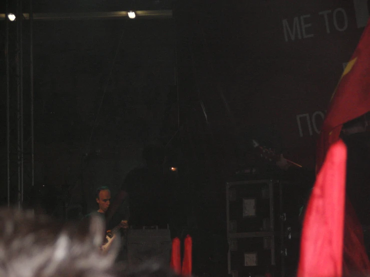 man on the stage playing guitar while people watch