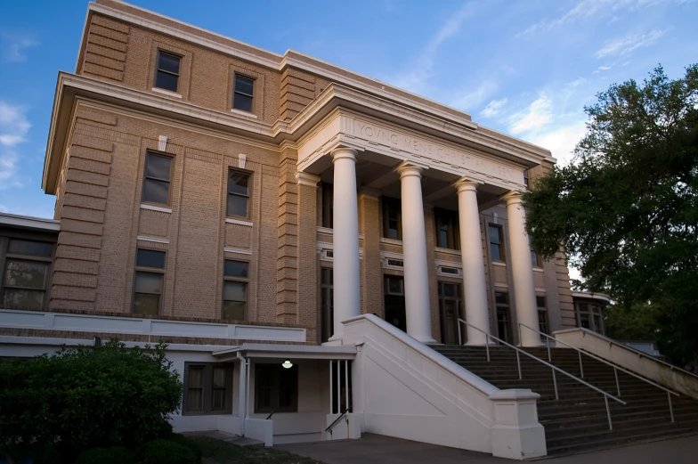 an old brick building with three columns and several stairs