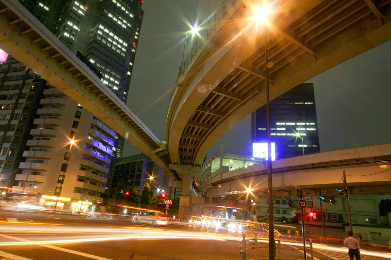 a city skyline at night with buildings and a lit up highway overpass