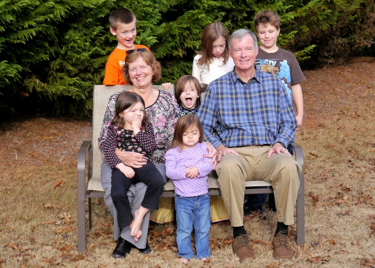 the family is all sitting on a bench together