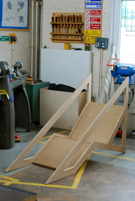 a wooden car sits in a garage with tools and other work