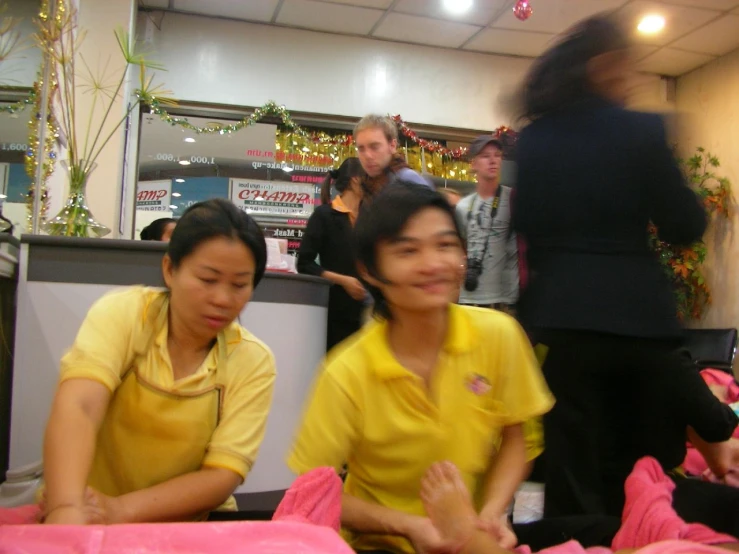 two asian women in yellow shirts and one is looking to her side