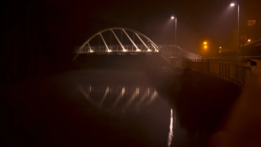 bridge lit up over water in fog and the street lights lit up