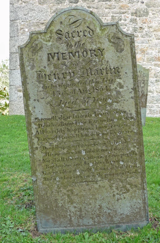 a tombstone of a couple of people that are standing in the grass