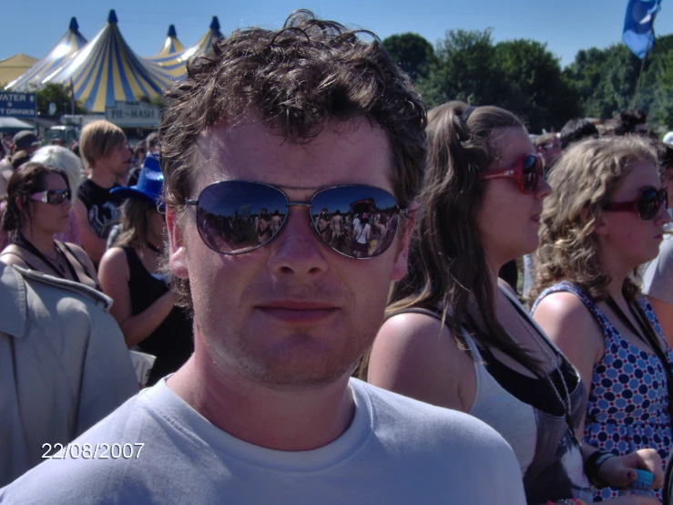 a person wearing sunglasses standing near an crowd