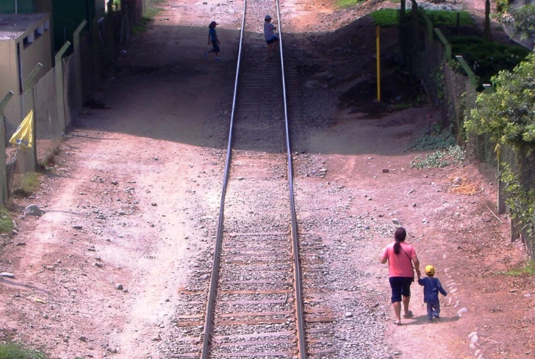 a couple of s walking on top of train tracks