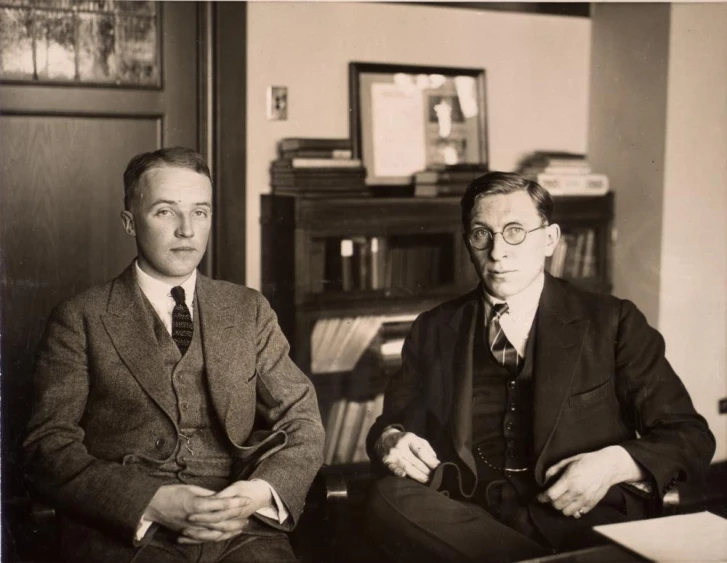 two men sitting next to each other in a living room