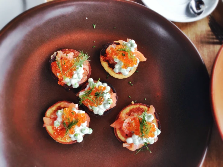 some food on a brown plate is placed next to a cup