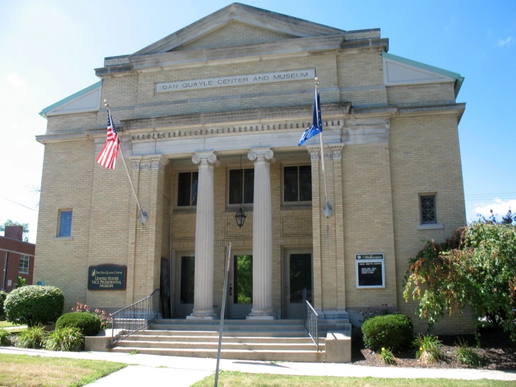 two flags are flying on a pole in front of a building