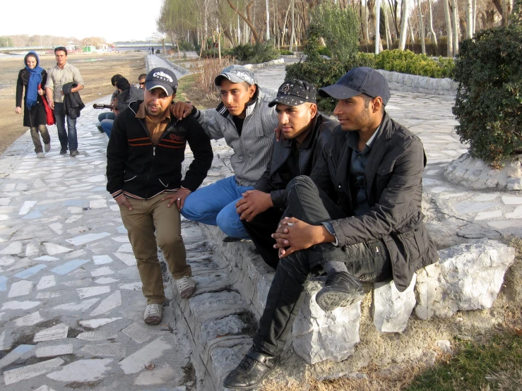 four people are sitting on a stone bench