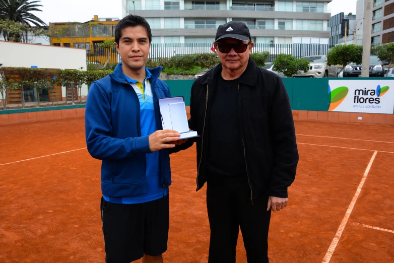 the man is showing off his medal to the tennis player