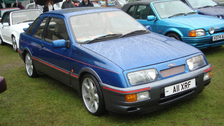 a small blue car parked next to other cars