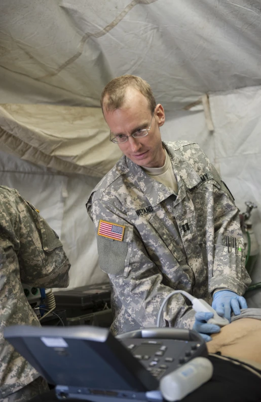 two military men in fatigues are working on a laptop