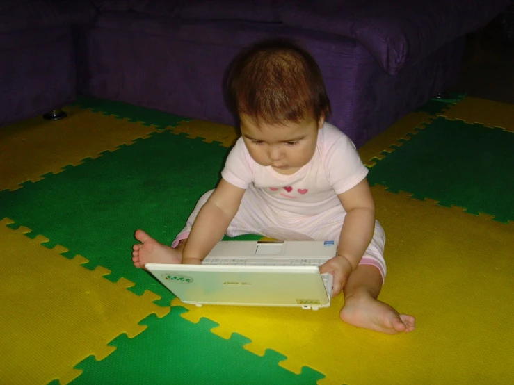 a baby on a floor with a laptop