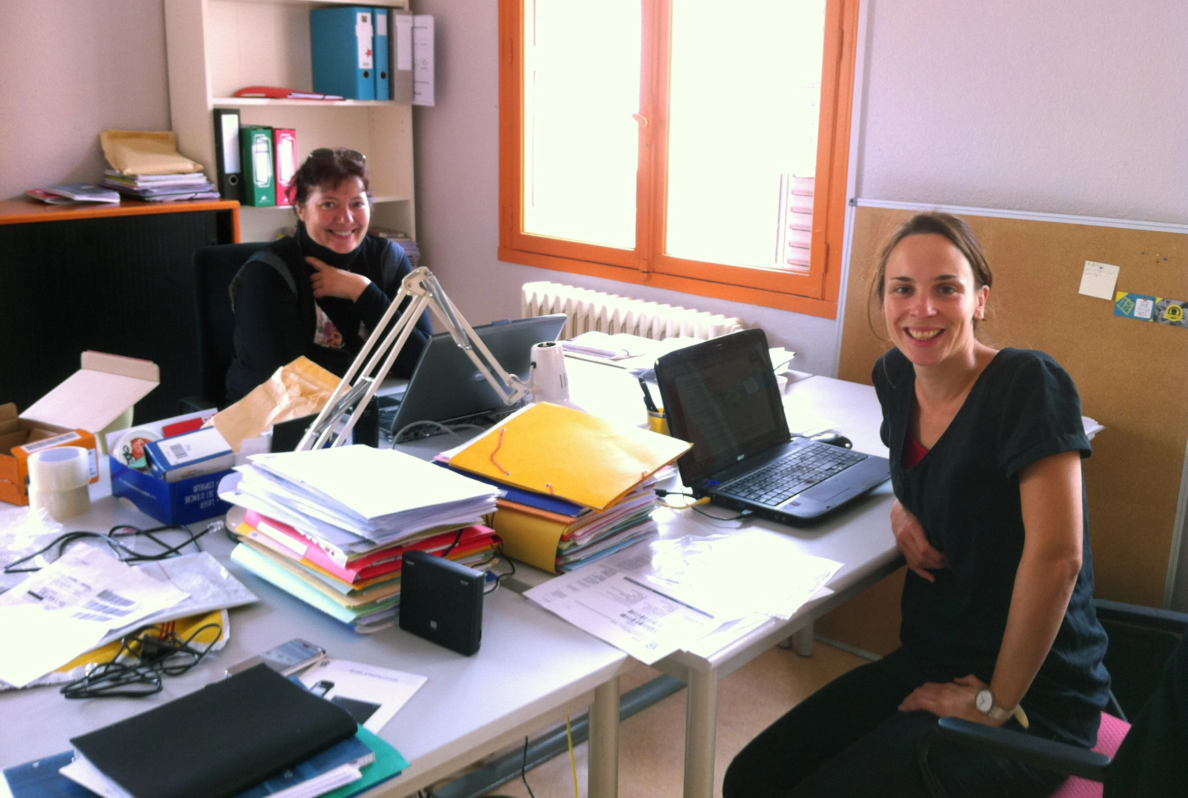 two people at a desk with laptops on it