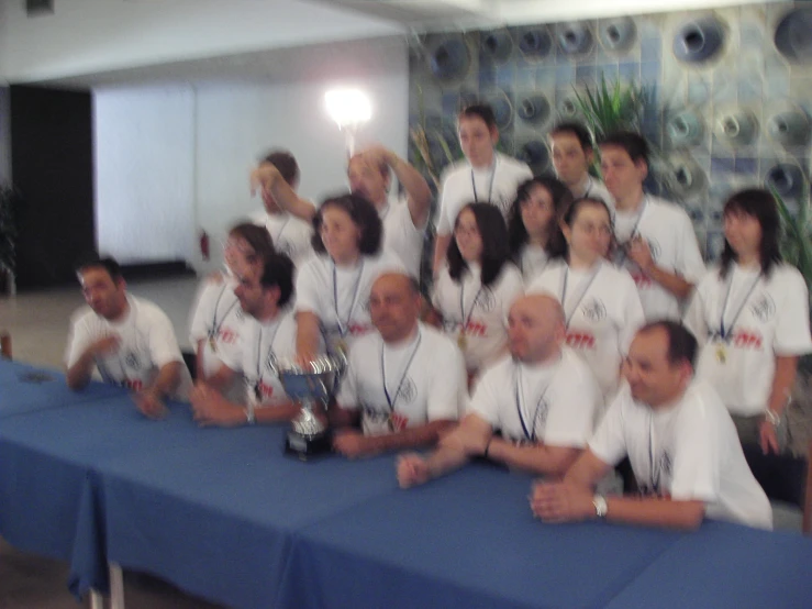 group of men and women sitting behind a blue table