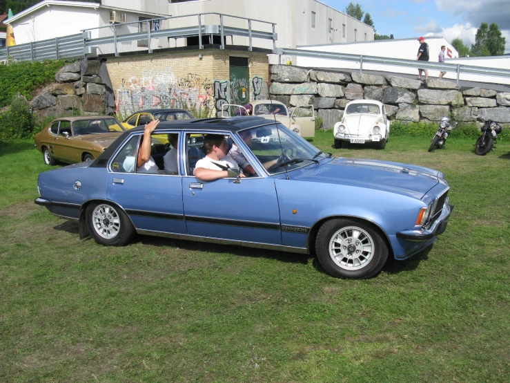 a woman sitting in a blue convertible looking out a car window