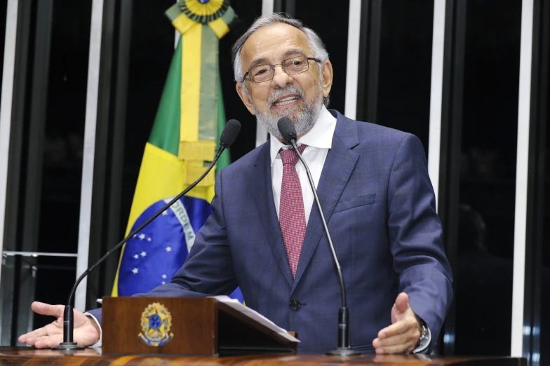 a man giving a speech at a podium in front of flags