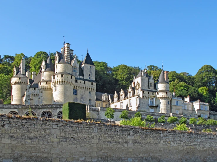 a castle on a hillside is viewed through an old wall