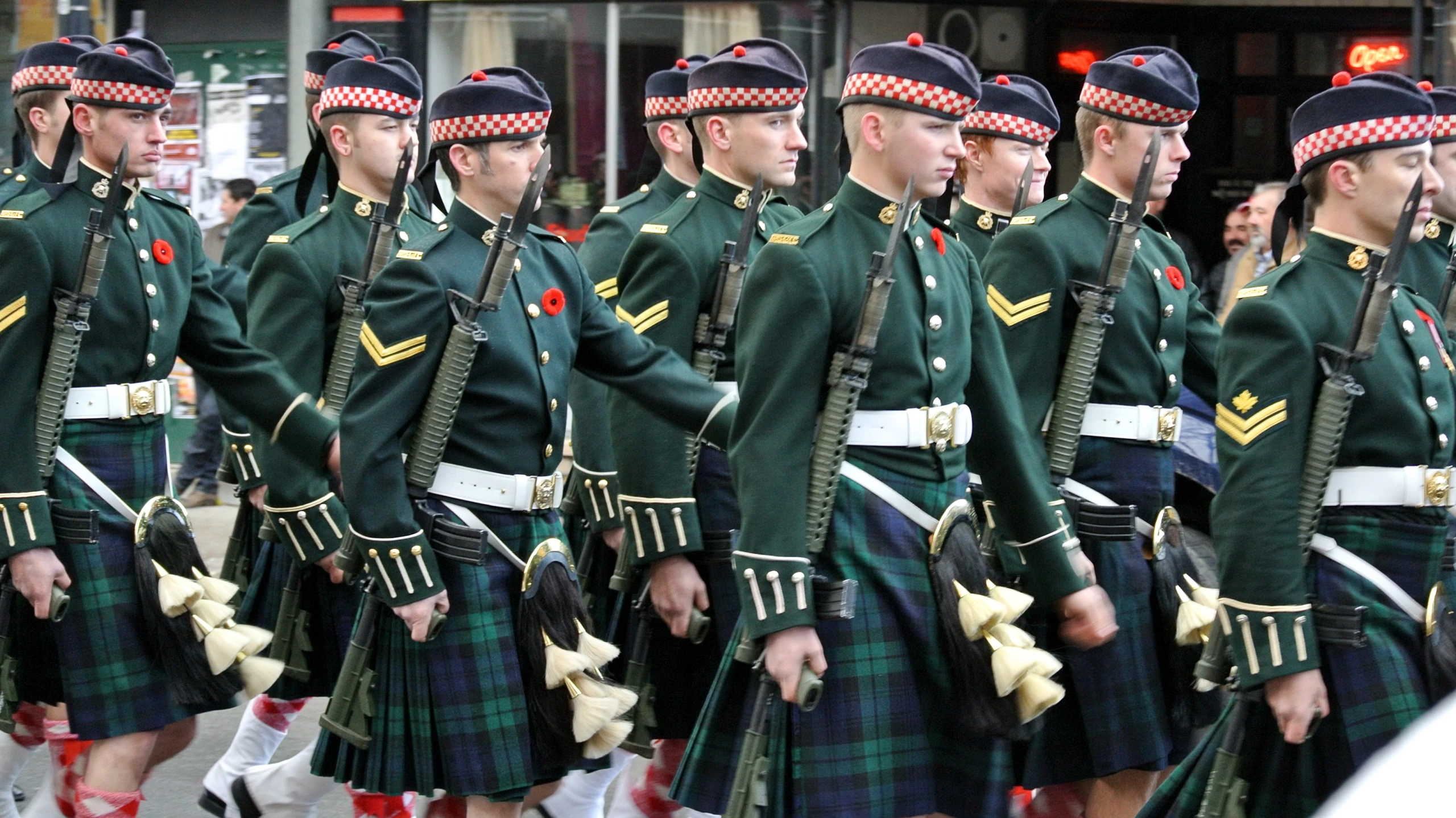 a row of military marching in green uniforms