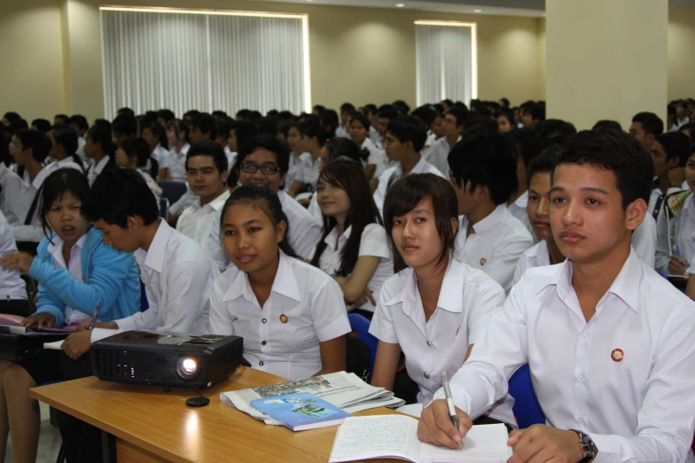 people in uniform are seated at desks and listening to speakers