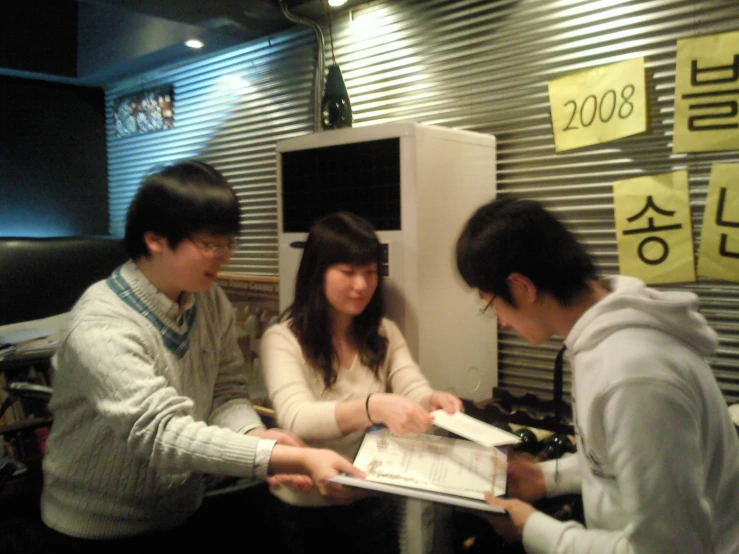 three people are standing together looking through some paper