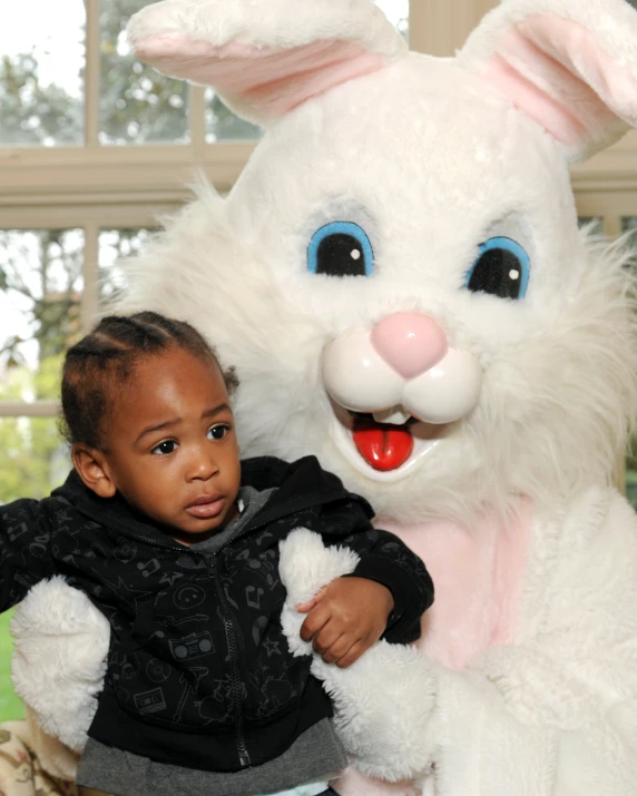 a little girl standing next to a large white easter rabbit