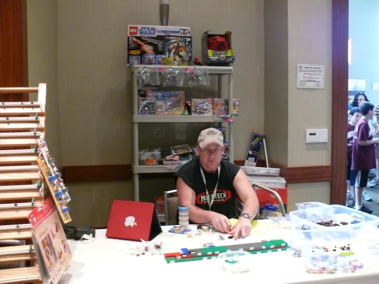 an older person sitting at a table with lots of toys