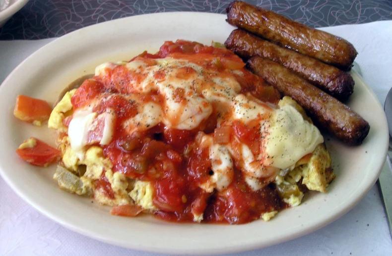 a plate with eggs, bacon and tomato on it