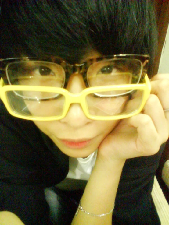 a woman with short black hair, wearing yellow glasses