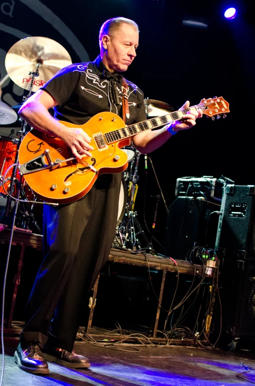 a man playing a guitar on stage at night