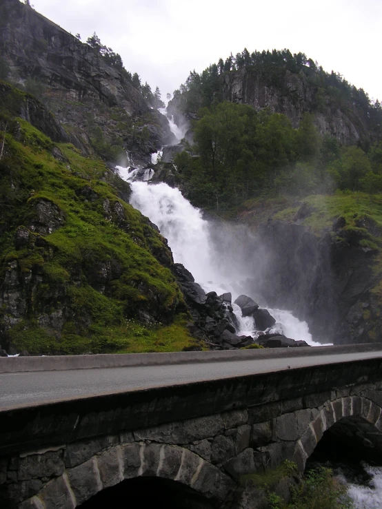 the side of a road with a bridge near a waterfall