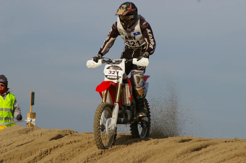 a man riding a dirt bike over a sandy hill