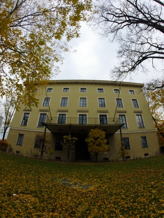 a large yellow building sits in the fall foliage