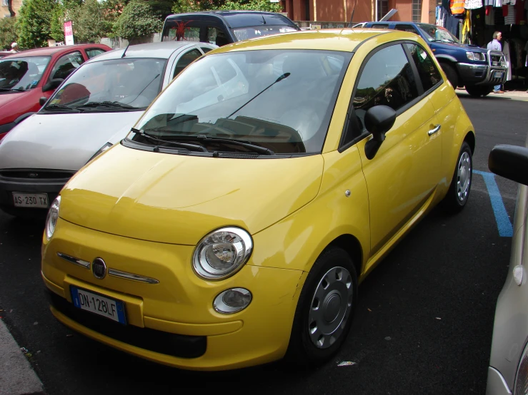 a yellow compact car is parked on the street
