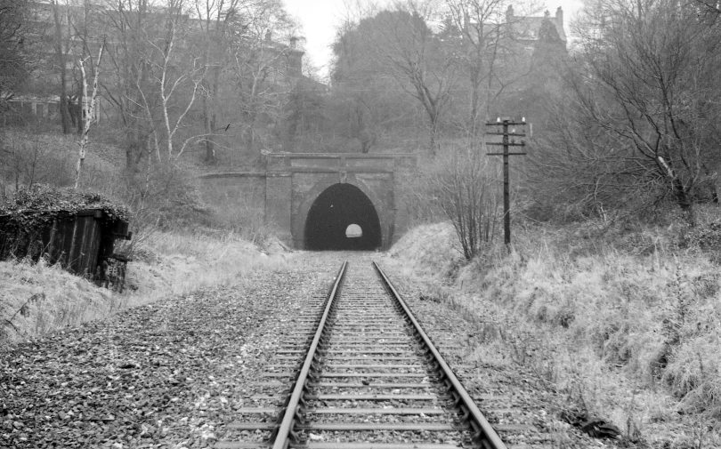 a train track passing through a tunnel with an iron beam