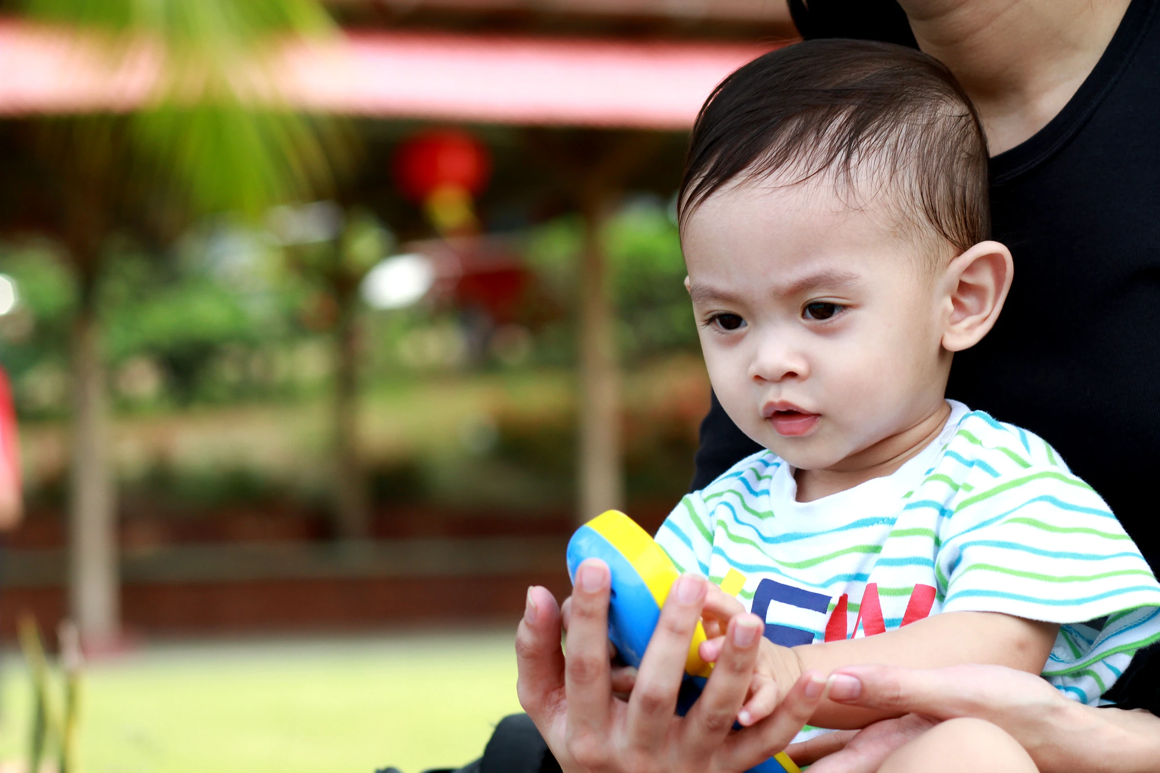 a woman holding a baby with a toy in his lap