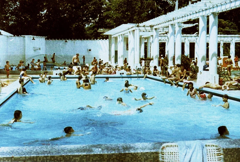 people are in the swimming pool by some white columns