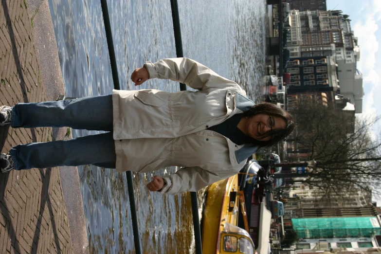 a woman is standing on the sidewalk near the water