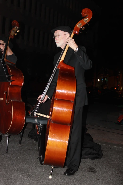 a man holding two double bass standing next to each other